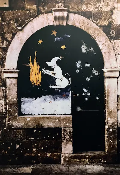 Porte ancienne avec impacts de guerre et un dessin de chien, illustrant le deuil animalier et déni comme mécanisme de protection.