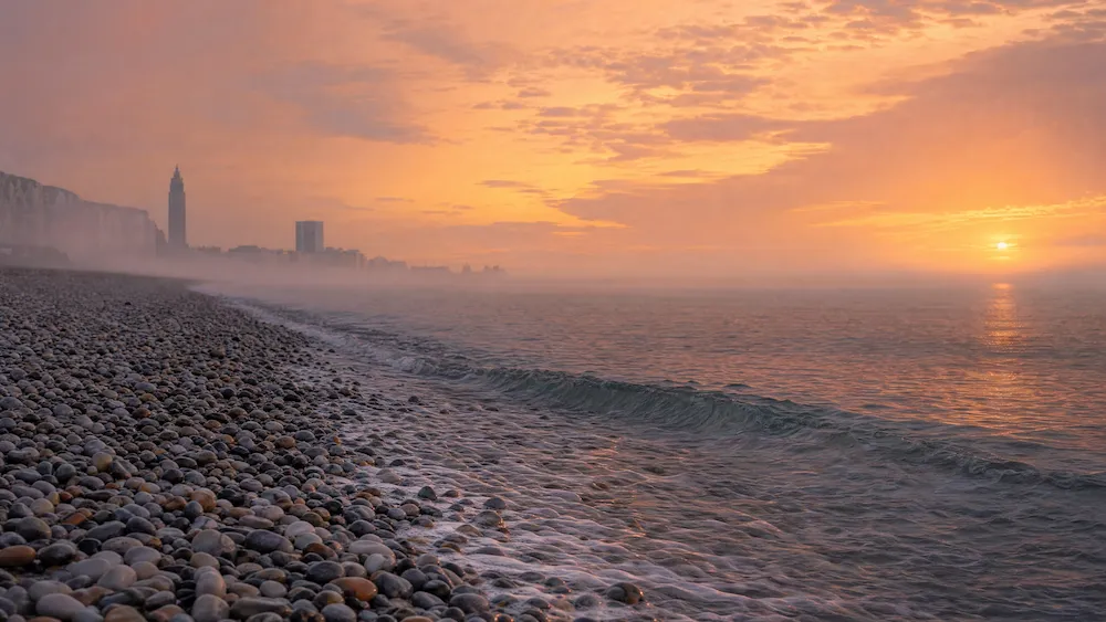 La plage de galets du Havre sous une lumière douce de fin de journée, symbolisant l'horizon et le chemin vers l'apaisement dans le deuil animalier.